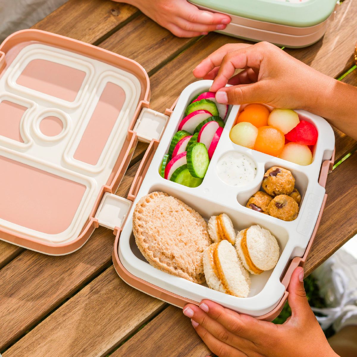 Bento box with compartments of food on a wooden table