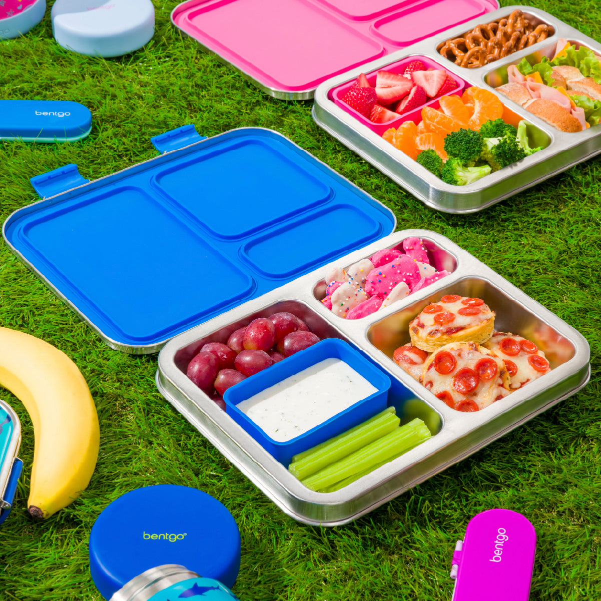Colorful bento boxes with compartments filled with food on a grassy background